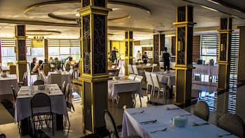 Un restaurante con mesas redondas, sillas y un camarero.