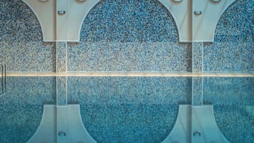 Una piscina con un muro de azulejos que presenta diseños circulares y un reflejo nítido.