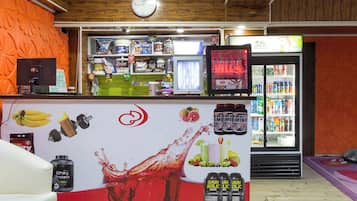 A reception area with a counter displaying protein supplements, a clock, and a refrigerator stocked with beverages.