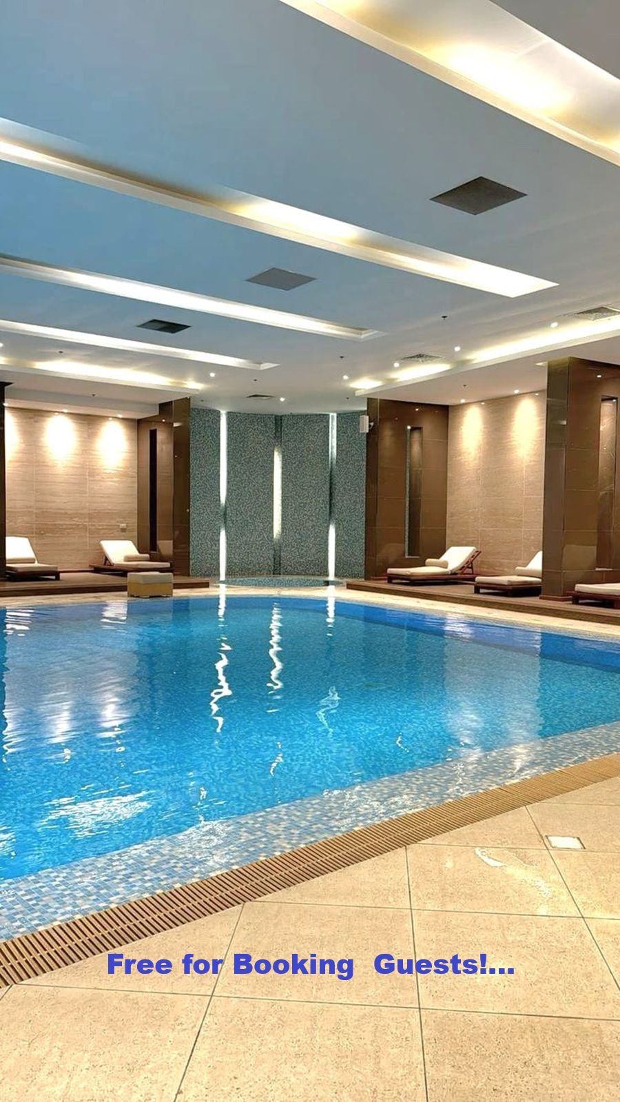 A large indoor swimming pool with lounge chairs and a tiled floor.
