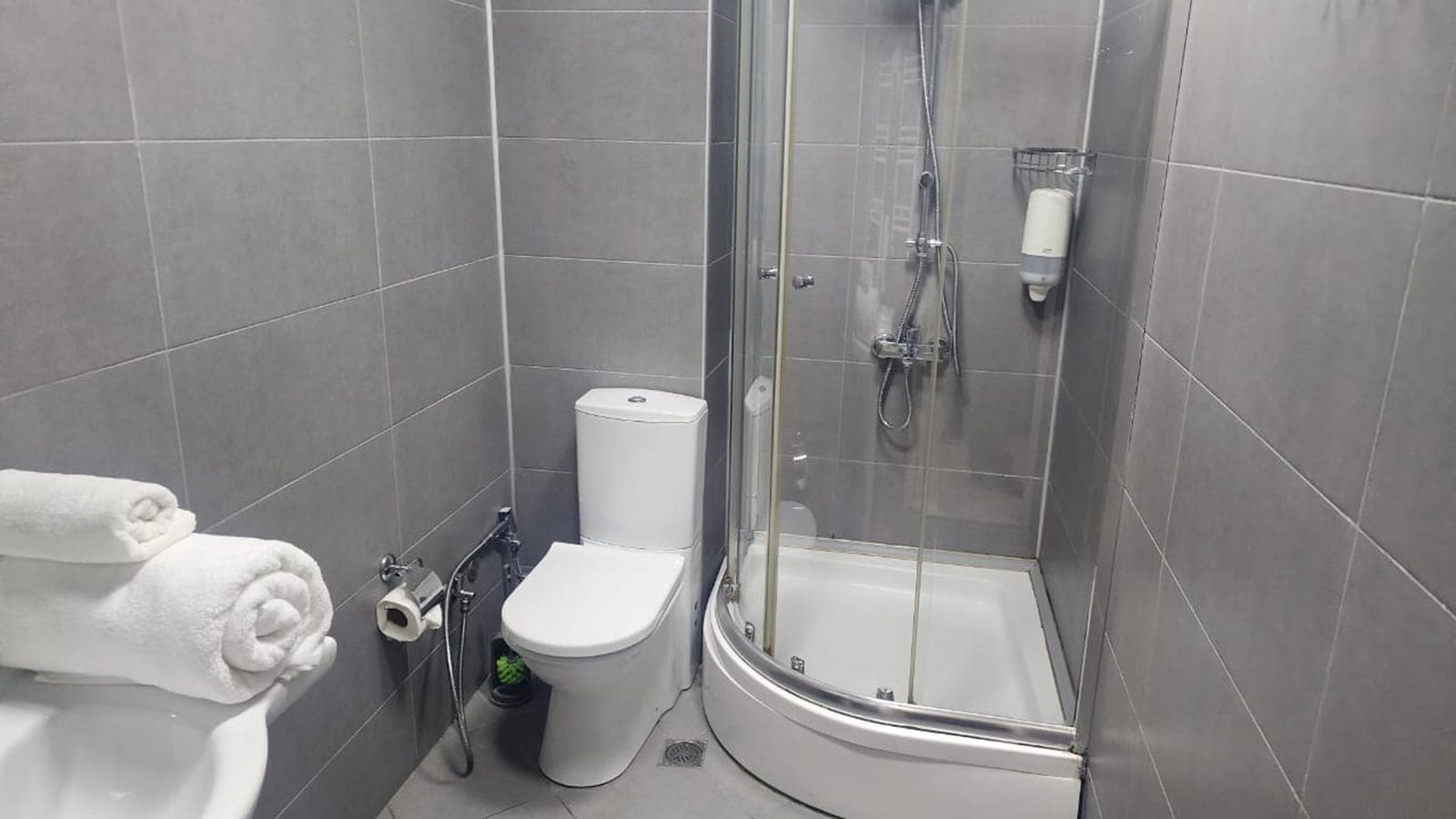 A modern bathroom with a toilet, shower, and two towels on the wall.