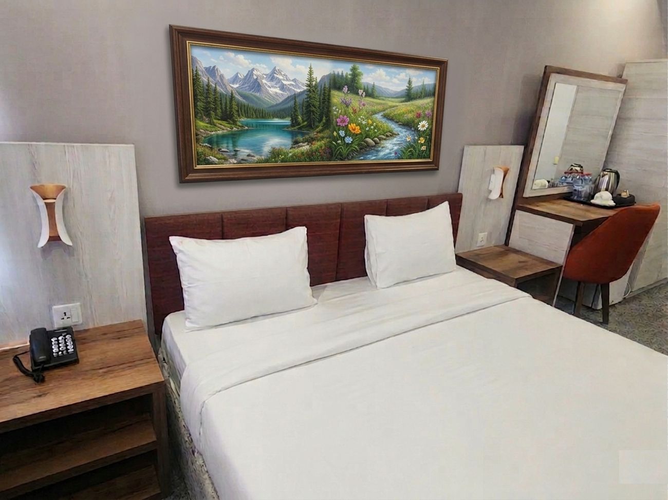 Habitación de hotel con cama, escritorio, silla, teléfono y un cuadro de un paisaje.