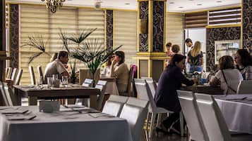 A restaurant with tables set for dining, a chandelier, and decorative wall panels.
