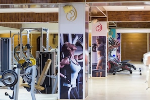 Un gimnasio con diferentes equipos de ejercicio, carteles y suelo de madera.