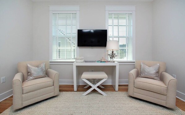 Una habitación con dos sillones, una mesita, un televisor y una ventana con persianas.
