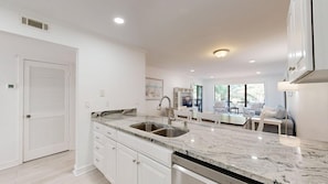A modern kitchen with a double sink, white cabinetry, and a marble countertop. - 89 The Moorings: 2  BR, 3  BA Villa in Hilton Head, Sleeps 6 (Hilton Head)