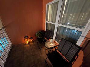 A balcony with a table and chairs, two lanterns, and a potted plant. - Cozy 1-bedroom condo in tranquil South Padre Island with Pool View ,beach access (South Padre Island)
