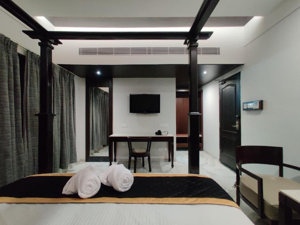 Une chambre d’hôtel avec un lit, un bureau, une chaise, une télévision et une porte.