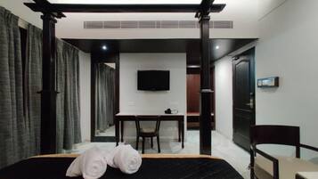 Une chambre d’hôtel avec un lit, un bureau, une chaise, une télévision et une porte.