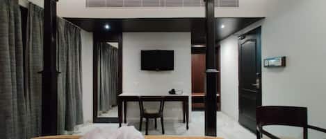 Una habitación de hotel con una cama, un escritorio, una silla, un televisor y una puerta.