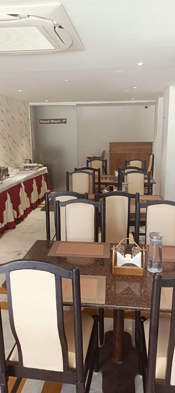 Un espace repas avec des tables et des chaises, un coin lavabo et un comptoir où sont rangés la vaisselle.
