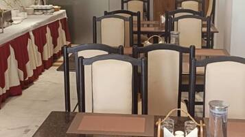 Un espace repas avec des tables et des chaises, un coin lavabo et un comptoir où sont rangés la vaisselle.