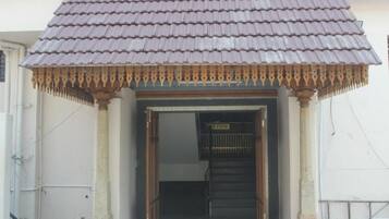 Entrada de um edifício com telhado em azulejos e um toldo decorativo de madeira.