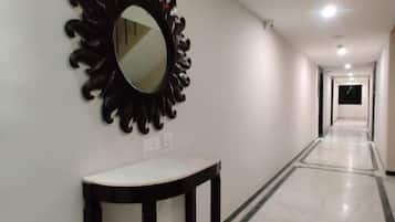 A hallway with a mirror on the wall, a small table, and a light fixture on the ceiling.