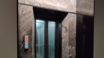 An elevator with a marble wall and a control panel with illuminated buttons.