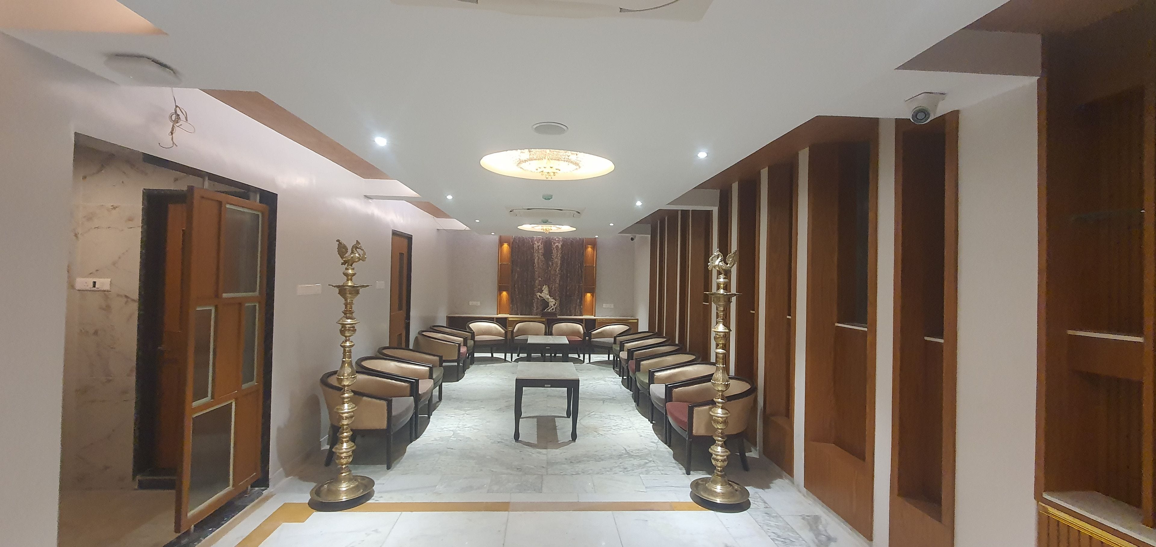 Un vestíbulo de hotel con piso de mármol, filas de asientos y un candelabro.