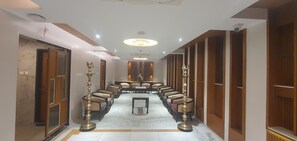 Un vestíbulo de hotel con piso de mármol, filas de asientos y un candelabro.