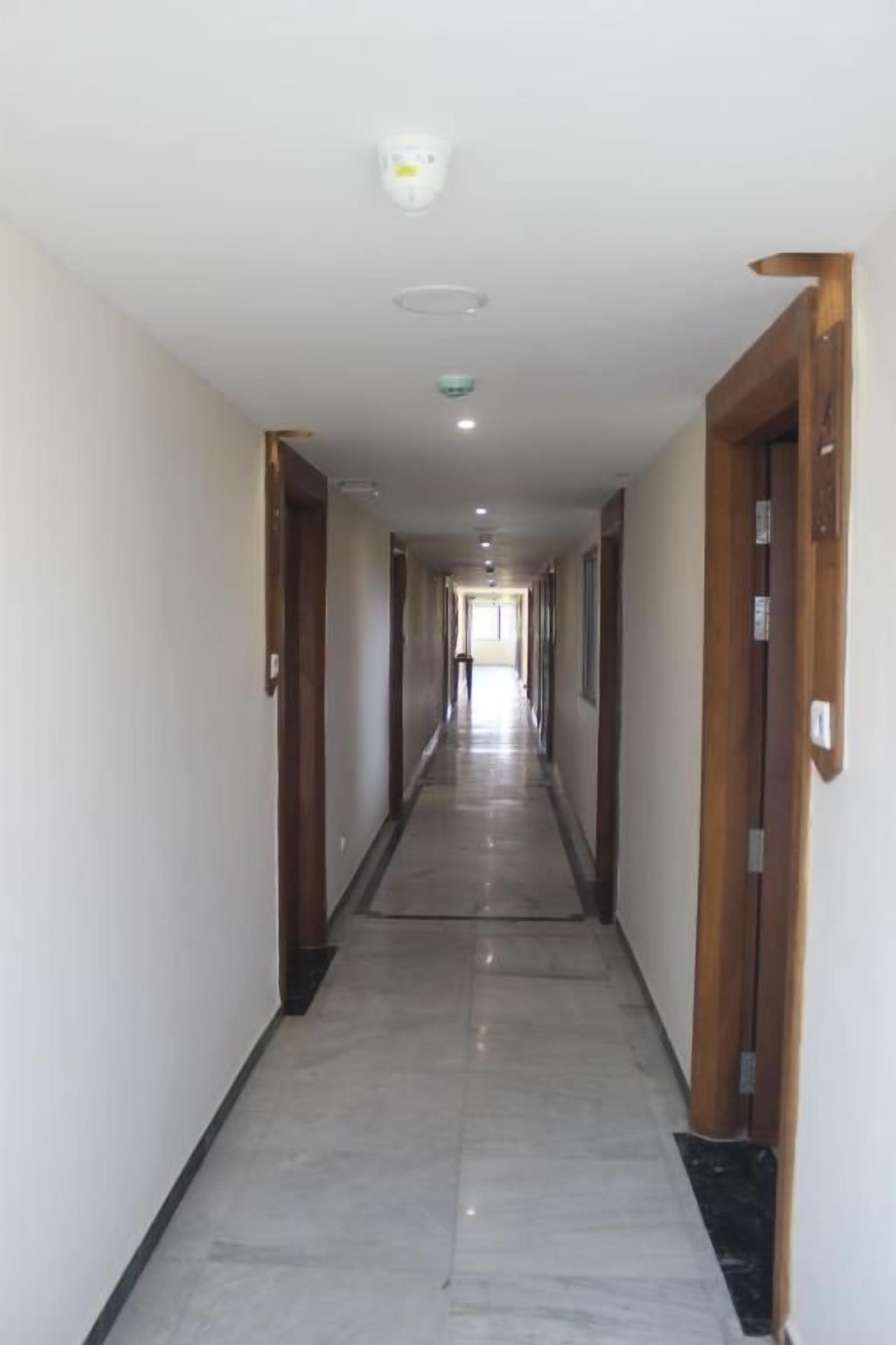 A long, narrow hallway with wooden doors on either side and a tiled floor.