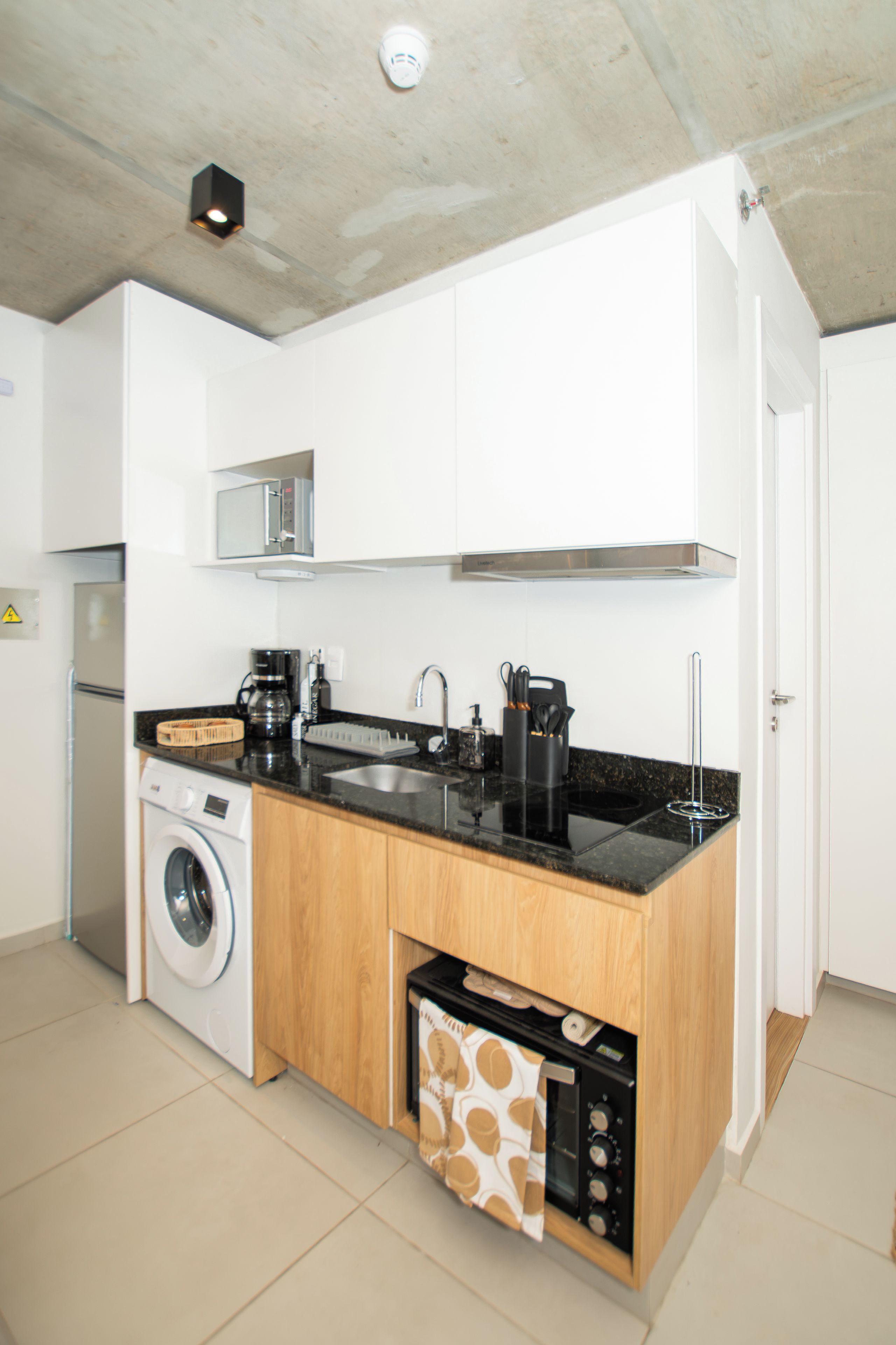 A modern kitchen with a washing machine, a microwave, and a built-in oven.