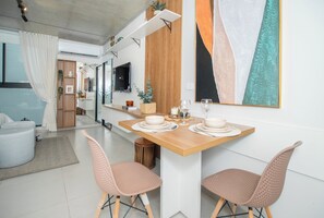 A modern dining area with a wooden table set for two, surrounded by wicker chairs. - Corporate Stays First del Sol - 604 (Asunción)