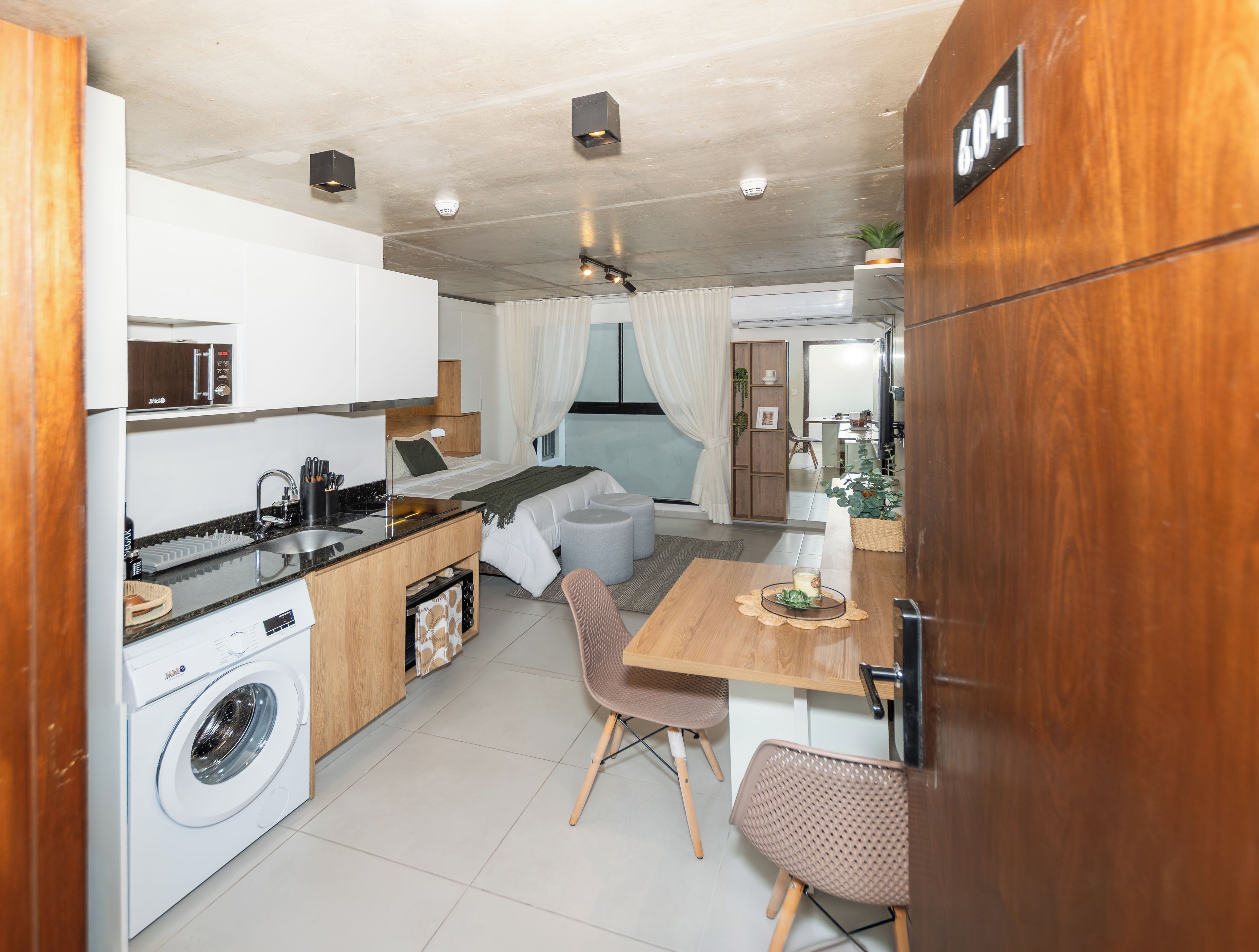 A compact living space with a kitchenette, a dining area, and a bedroom.