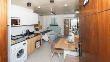 A compact living space with a kitchenette, a dining area, and a bedroom.