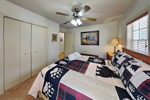 A bedroom with a bed, a ceiling fan, a window with blinds, a door, and a wall-mounted painting. - Gonzo Chalet | Spacious Deck + Mountain Views (Ruidoso)