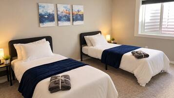 Quarto de hotel com duas camas, uma janela e obras de arte na parede.