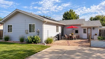 A single-story house with a patio area, a covered grill, and a red umbrella.