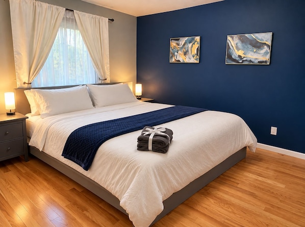 A hotel room with a bed, bedside lamps, a window with curtains, and two abstract paintings on the wall. - Palisade Mountain Retreat | Gather & Unwind (Windsor)