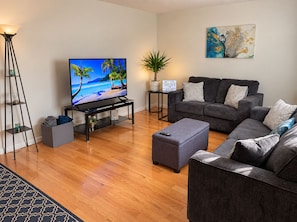 A living room with a TV, grey sofas, a coffee table, a floor lamp, and a potted plant. - Palisade Mountain Retreat | Gather & Unwind (Windsor)