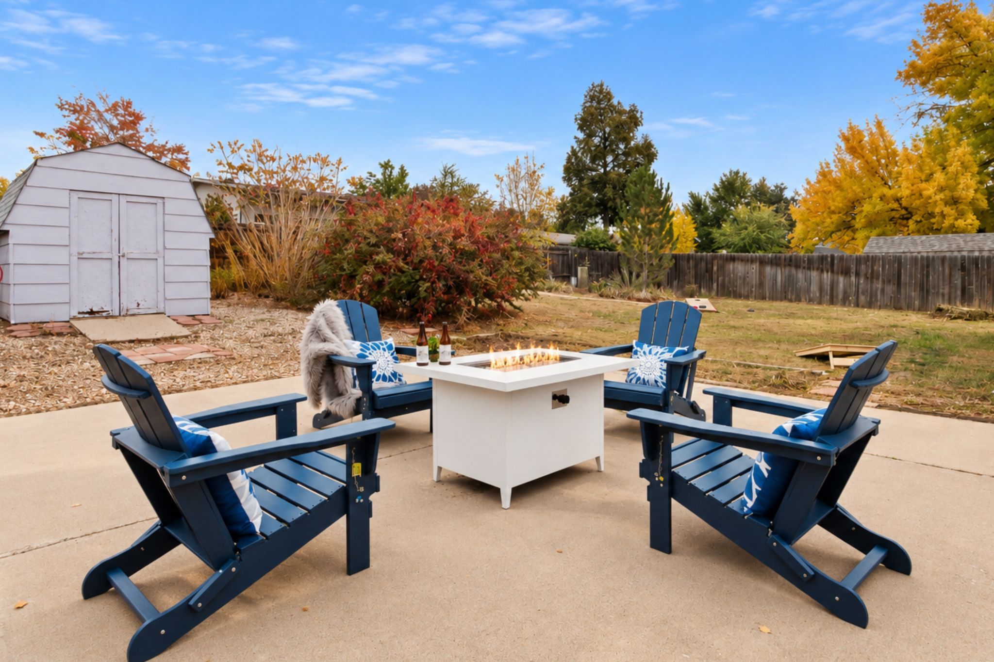 An outdoor seating area with Adirondack chairs and a central fire pit.