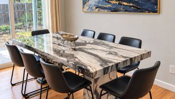 A dining area with a marble table, black chairs, and a painting on the wall.