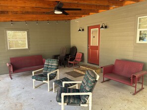 Ein überdachter Außenbereich mit Deckenventilator, zwei roten Sofas und gemusterten Stühlen.