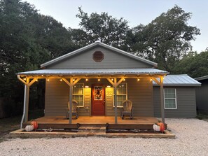 Una casa con un portico, una porta rossa e un cartello di benvenuto.