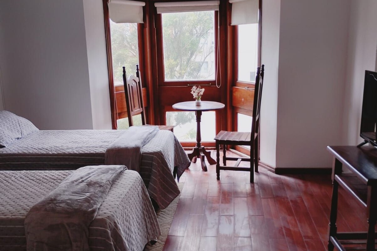 A room with two beds, a small table with a chair, and a television.