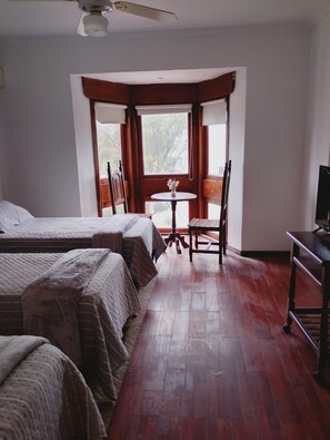 A room with two beds, a small table with a chair, and a television. - Bakumare Hotel (Pinamar)