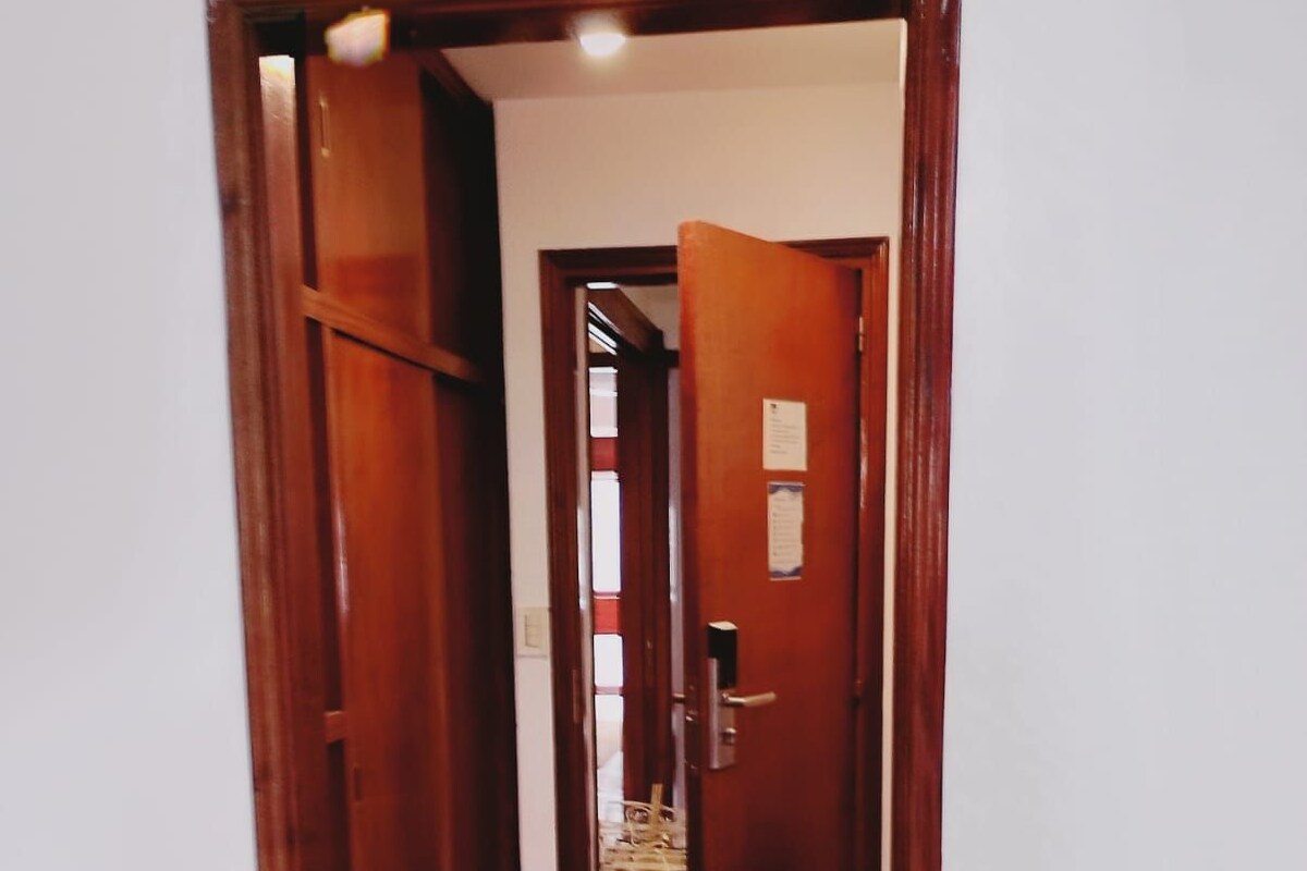 A wooden door leading to a room with a bed and a visible window.