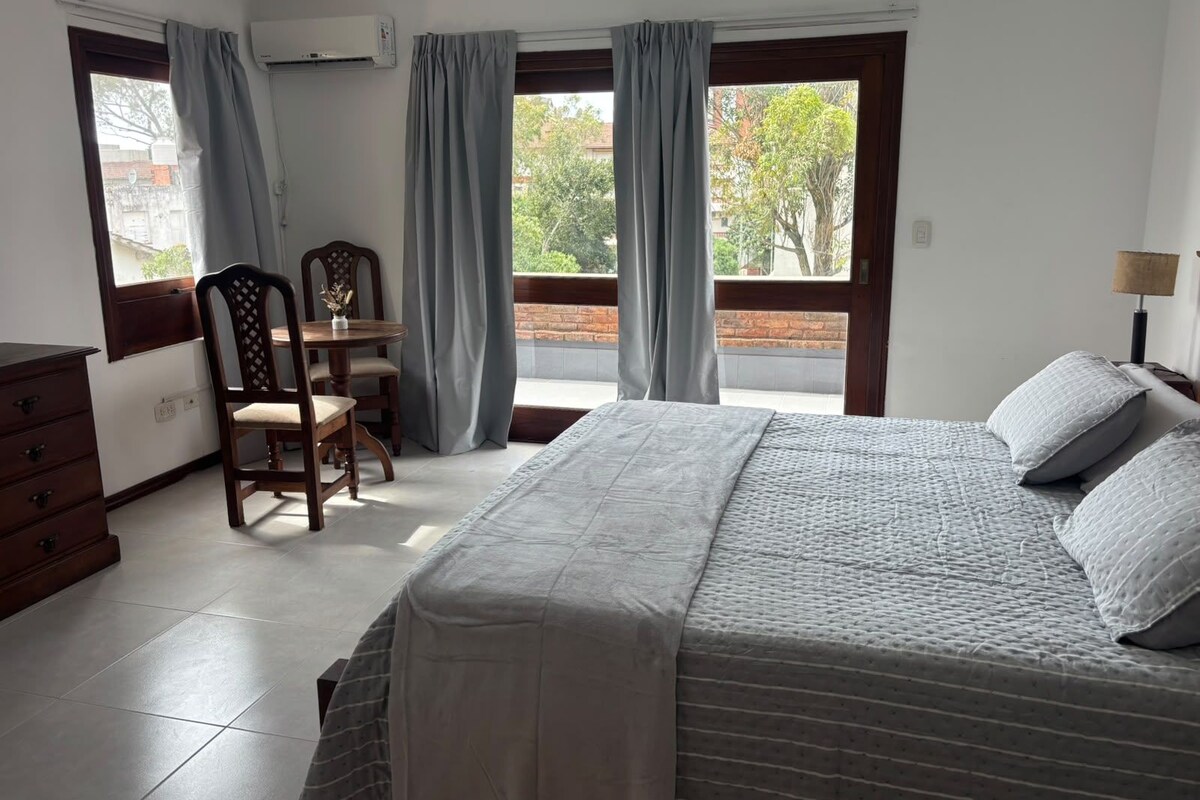 A bedroom with a bed, a desk, a chair, and a dresser.