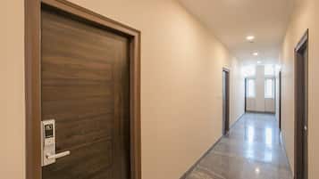 Un couloir avec une porte en bois sur la gauche, un interrupteur et une porte sur la droite.