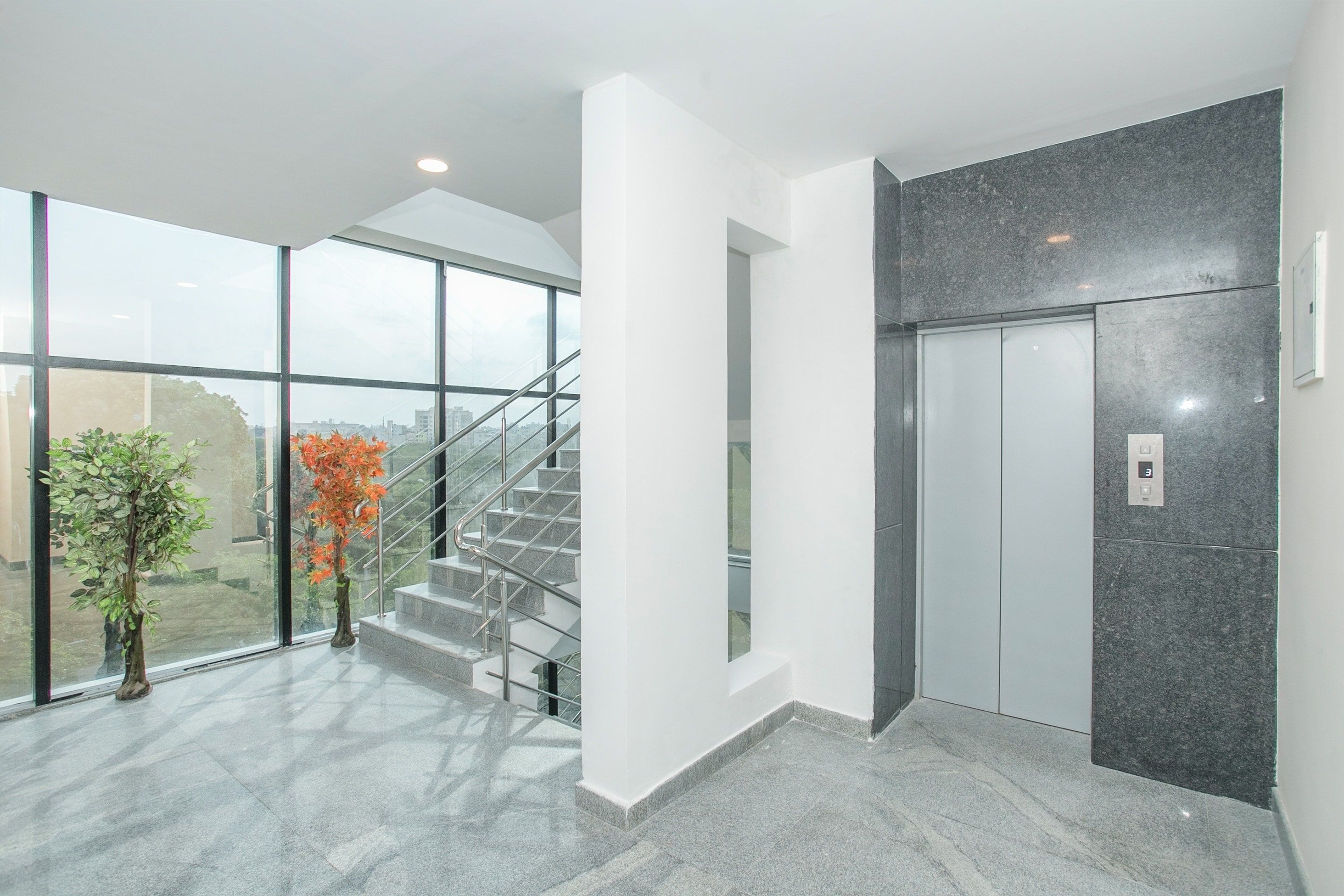 Un intérieur moderne avec un escalier, de grandes fenêtres et un ascenseur.