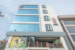 A multi-story building with a glass facade, a balcony with metal railings, and a mural on the lower level. - live on BLR3405 (Bangalore)