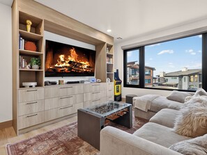 A modern living room with a fireplace, a large flat-screen TV, a sofa, and a coffee table. - Ski-In/Out Luxury | Private Hot Tub + Sauna (Brian Head)
