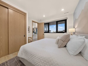 A bedroom with a large bed, a wooden wardrobe, and a window with a city view. - Ski-In/Out Luxury | Private Hot Tub + Sauna (Brian Head)