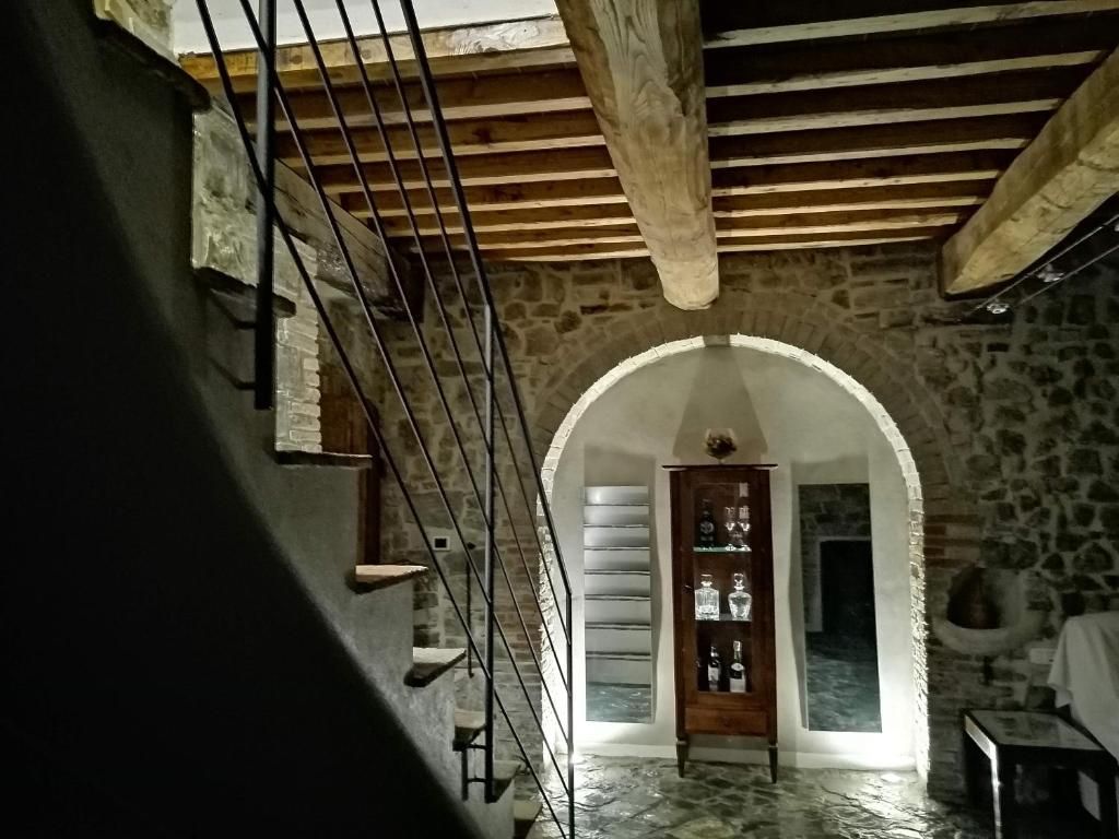 Habitación con paredes de piedra, una escalera de madera y una puerta que da a otra estancia.