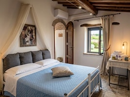 Un dormitorio con cama, mesita de noche con lámpara, ventana con cortinas y aire acondicionado instalado en la pared.