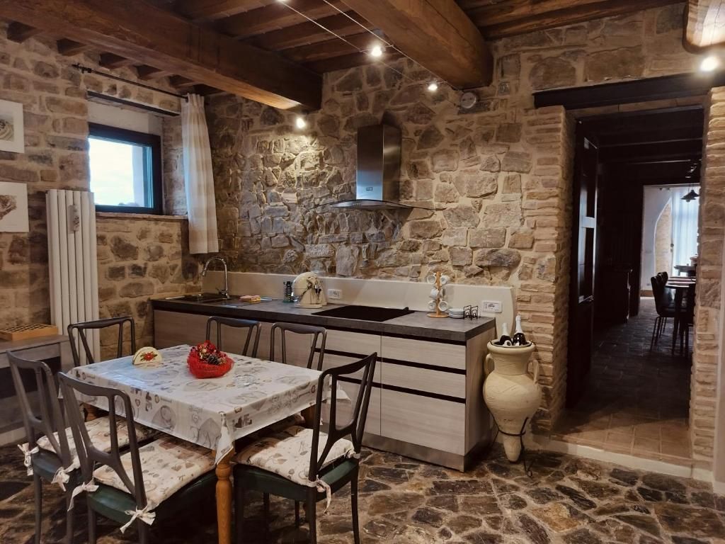 A rustic stone kitchen with a dining area, wooden beams, and a stone floor.