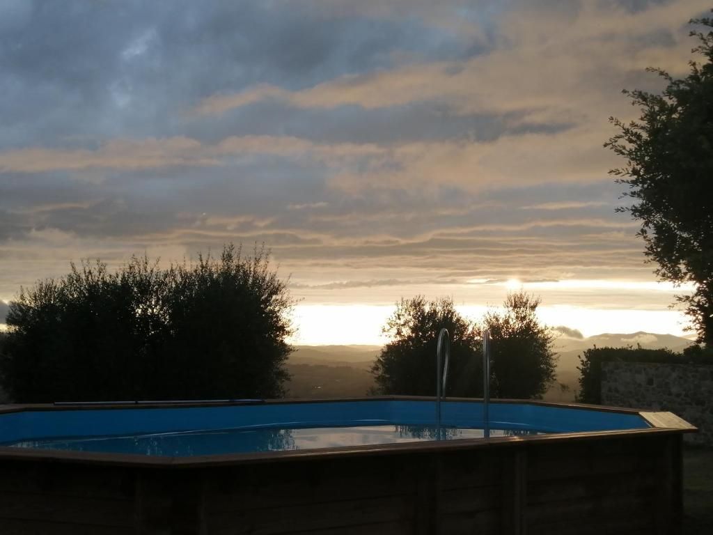 Una piscina con vistas a la puesta de sol y colinas distantes.
