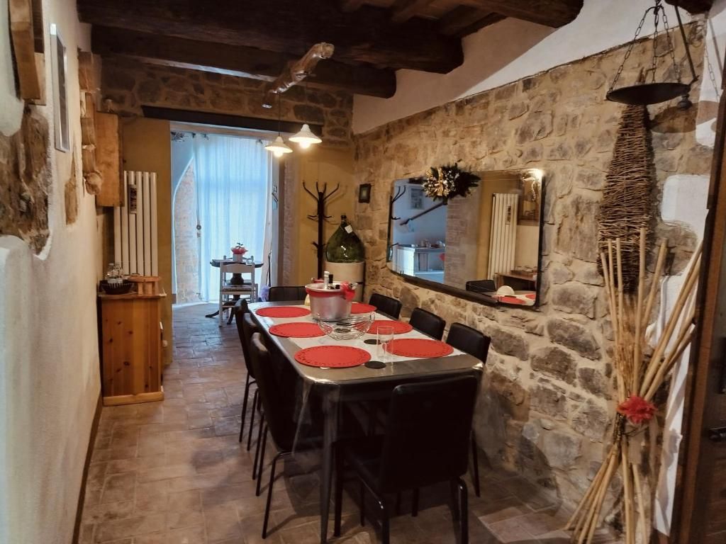 Un comedor con pared de piedra, una mesa de madera dispuesta para cuatro y un ambiente rústico.
