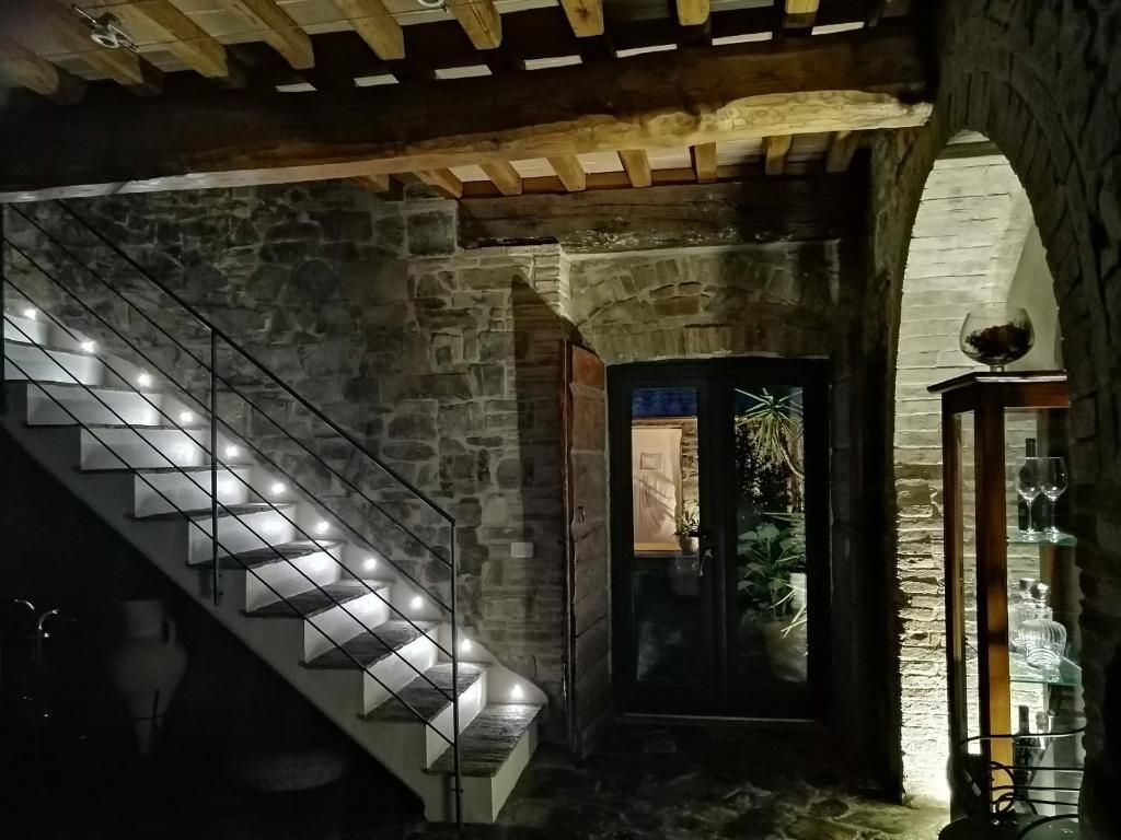 Una escalera de piedra iluminada con luces modernas que conduce a una puerta con panel de vidrio.
